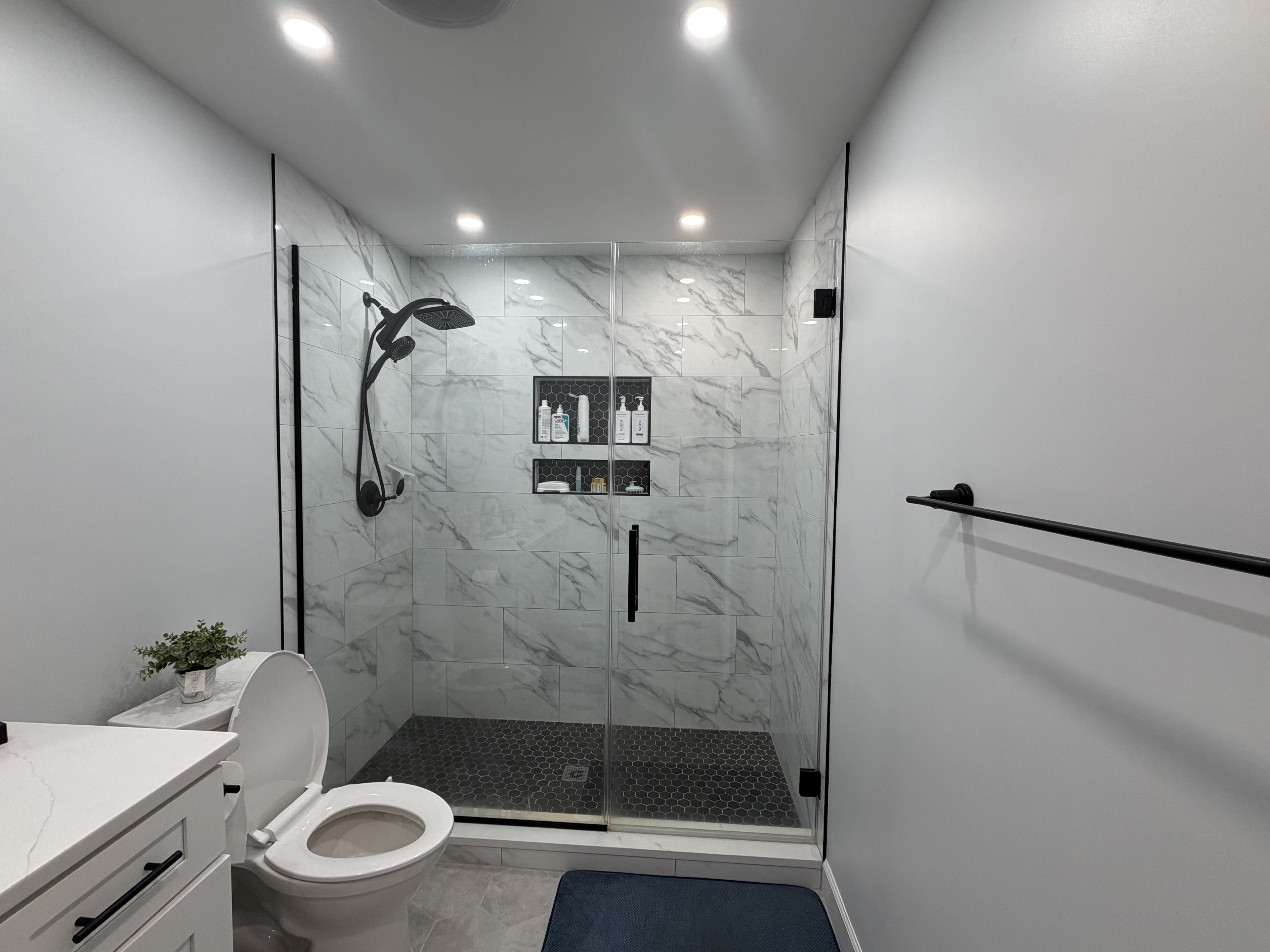 Marble walk-in shower with black matte fixtures and hexagon floor tile
